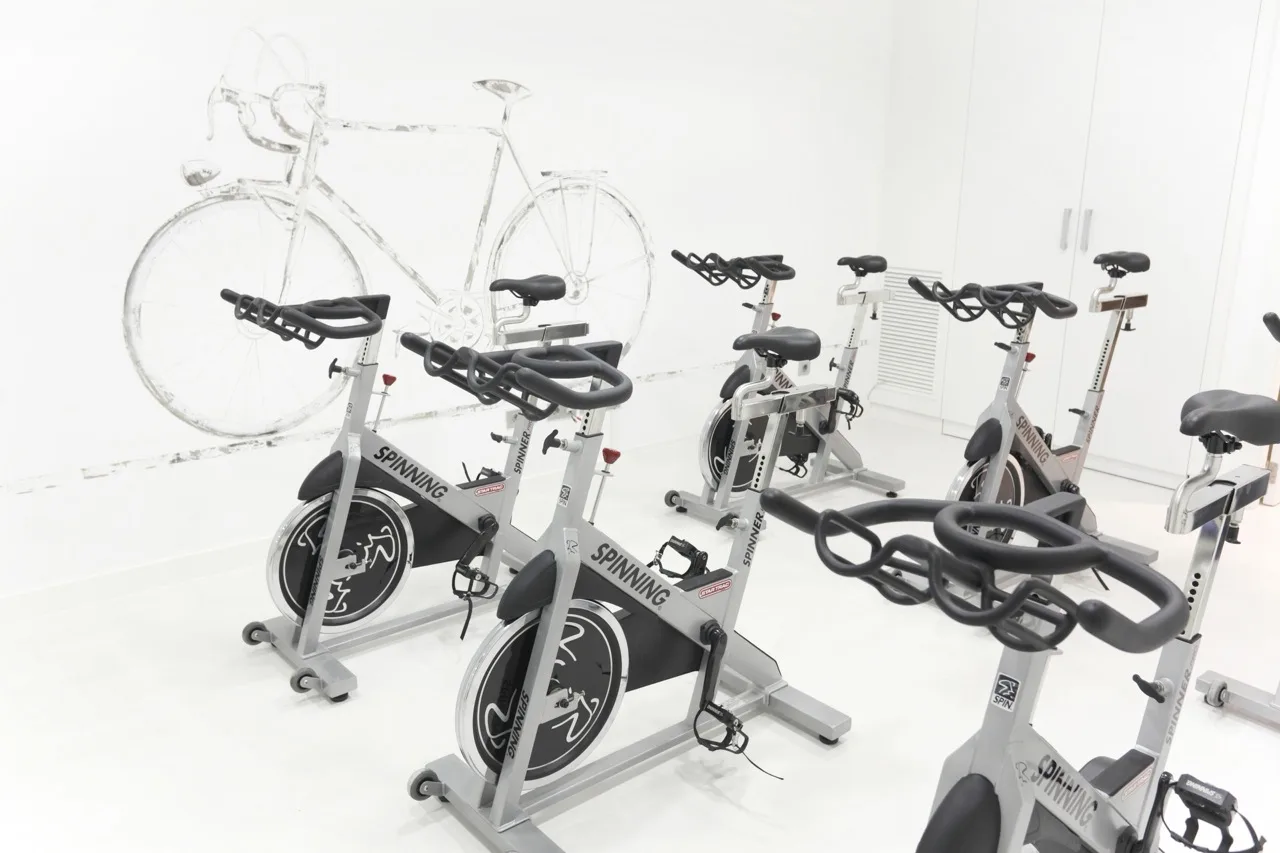 Stationary bikes in a bright white room at Hotel Ciutat de Girona, set up for indoor cycling or training