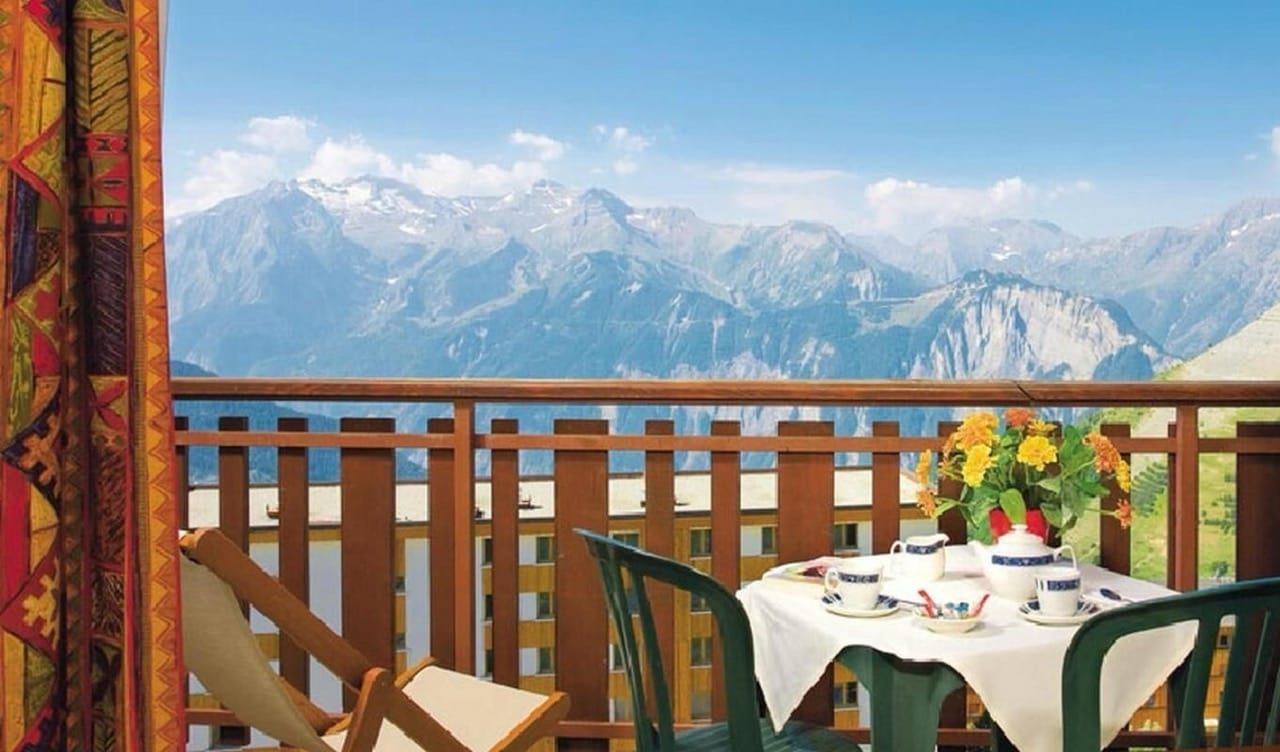 Table setup on balcony at Hôtel Le Castillan overlooking mountains with scenic views