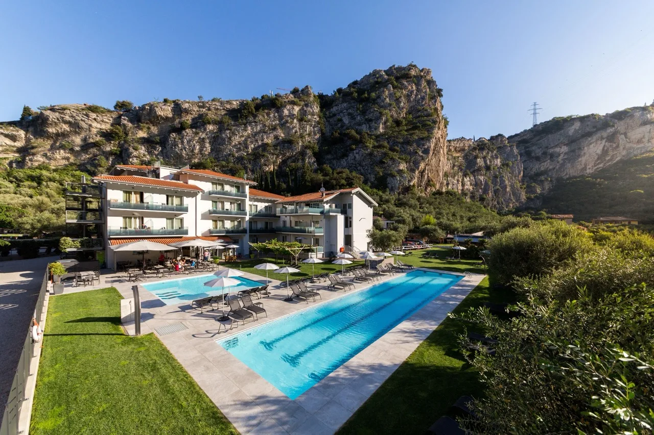 One long pool and a smaller pool at Aktivhotel Santalucia, Lake Garda with hotel and mountain backdrop