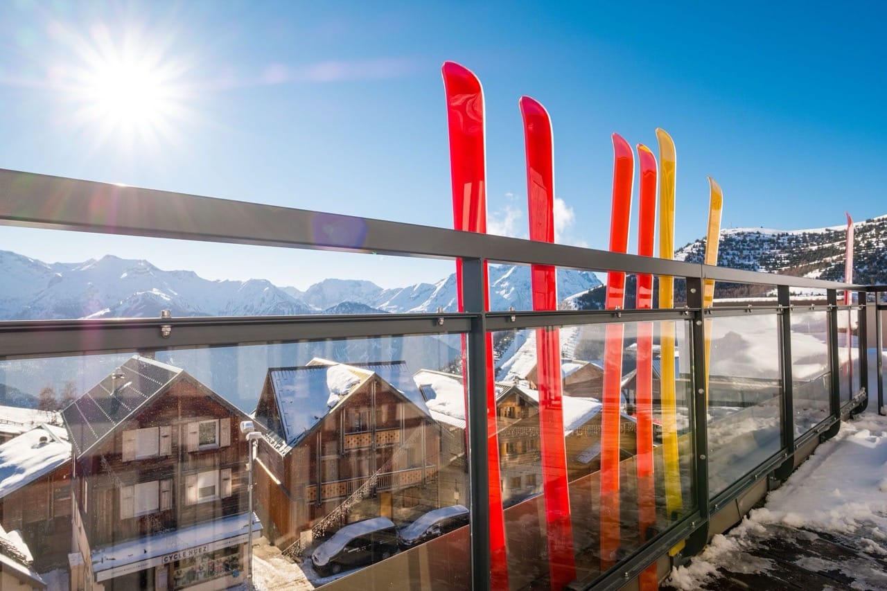 View from PopAlp balcony in Alpe d'Huez overlooking snowy mountains and nearby alpine style buildings