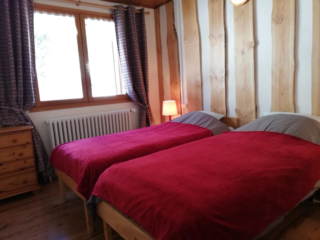 Small bedroom at Gite - Auberge Le Chamois with two single beds, red comforters, wooden design, large windows
