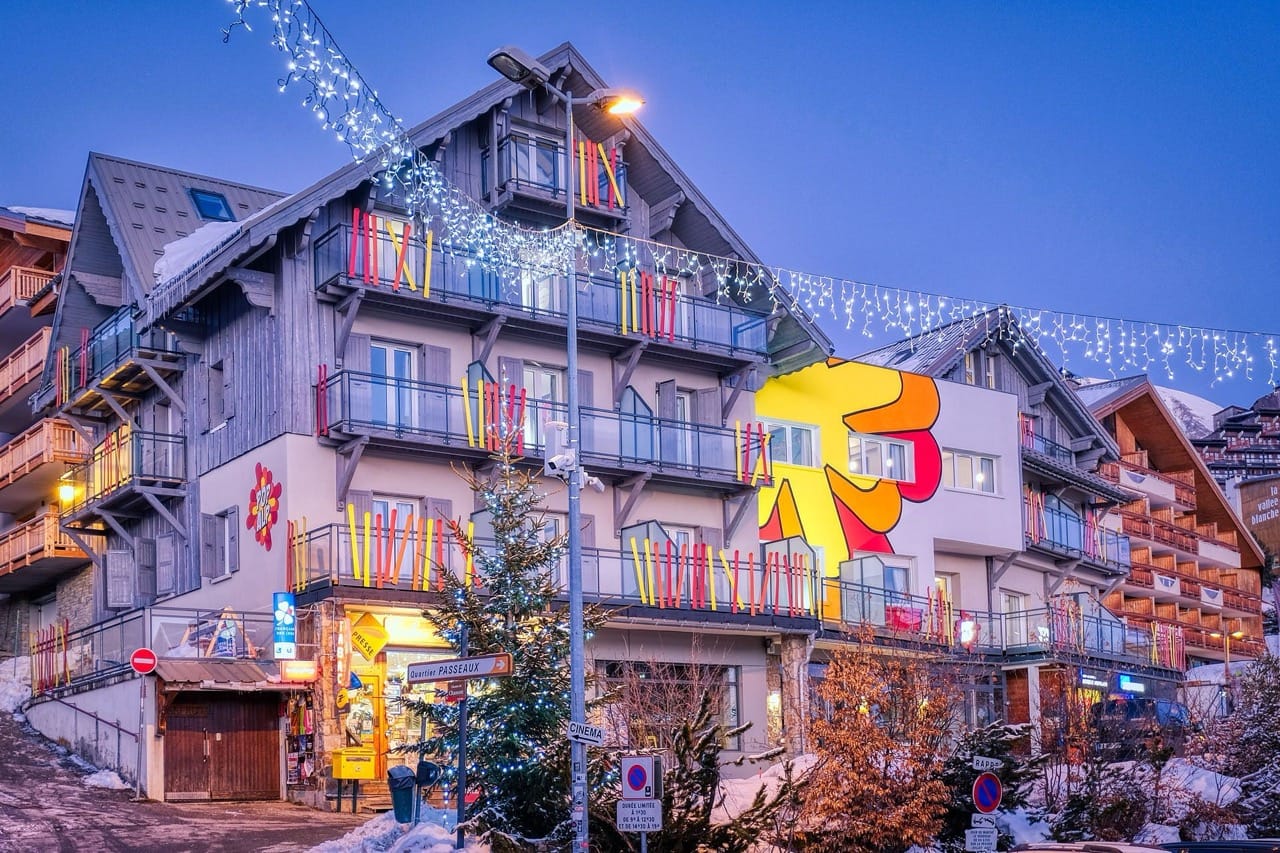 PopAlp building at Alpe d’Huez decorated with lights and colorful murals during twilight winter evening
