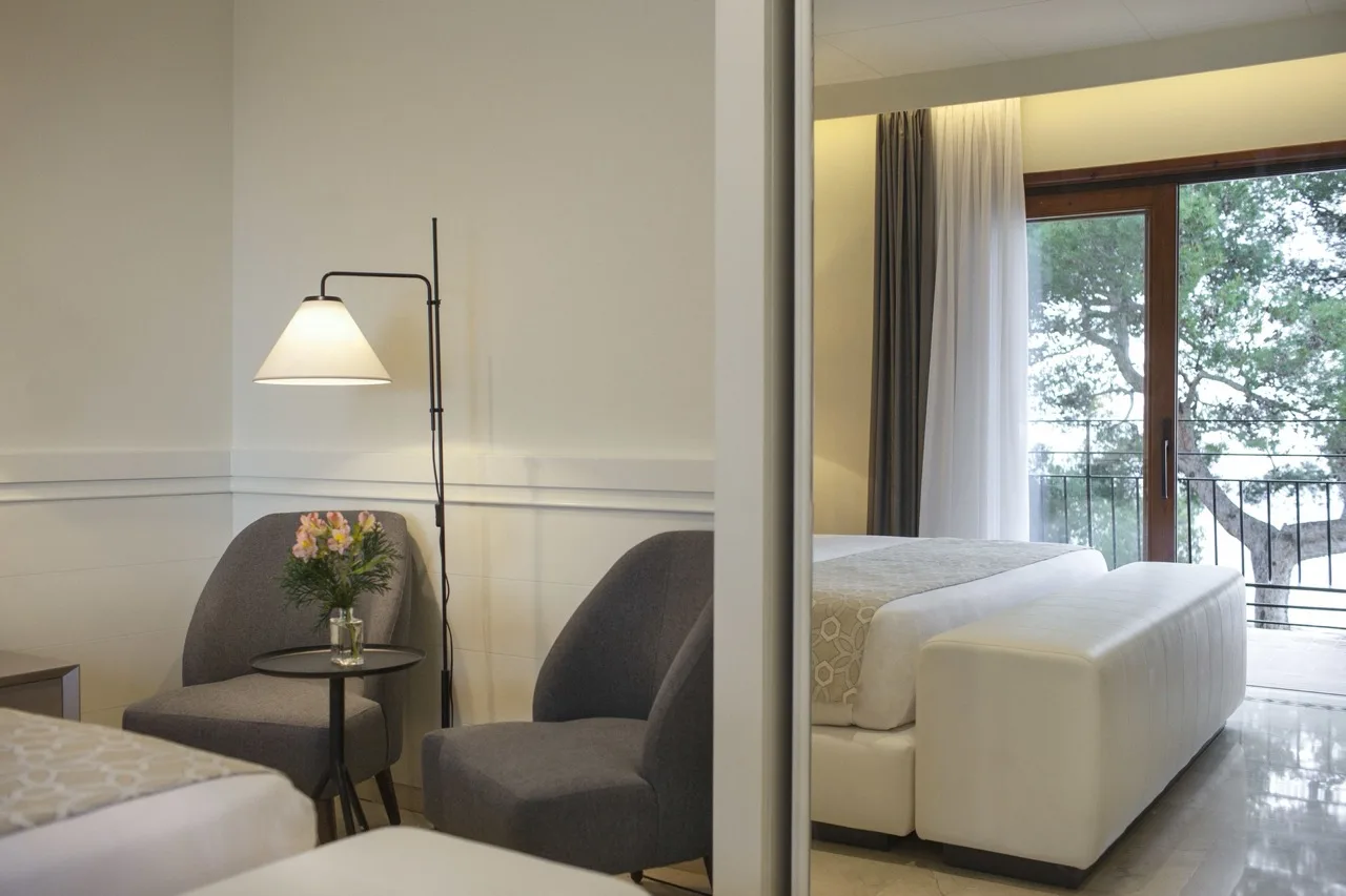 Bright suite at Hotel Santa Marta in Lloret de Mar with white walls, white furniture, and wood and gray accents