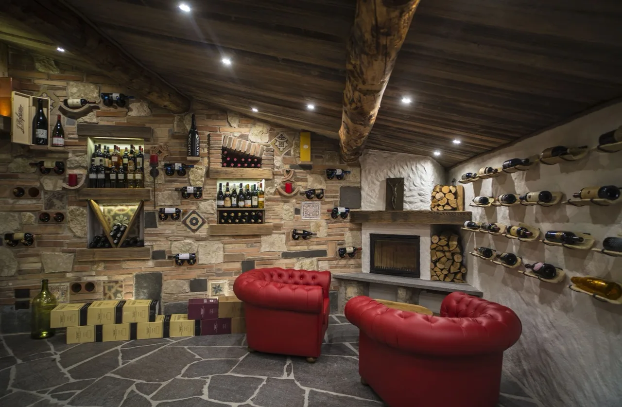 Wine room at Aktivhotel Santalucia, Lake Garda with wooden ceiling, rocky floor, red sofas, and accent chair