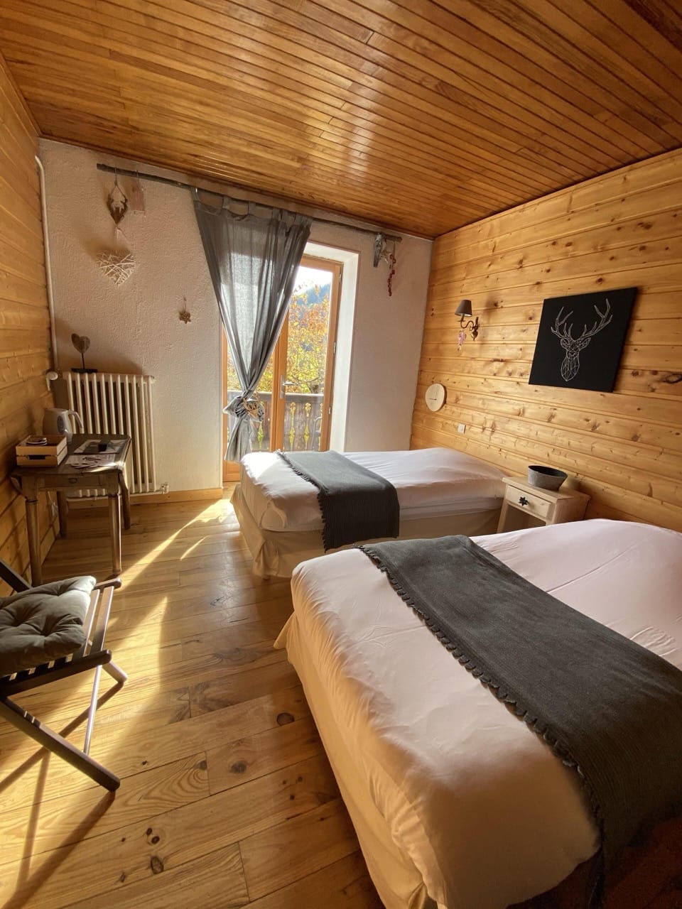 Bedroom at Auberge de la Forêt in Auris with two beds, wooden interior, and black accent details