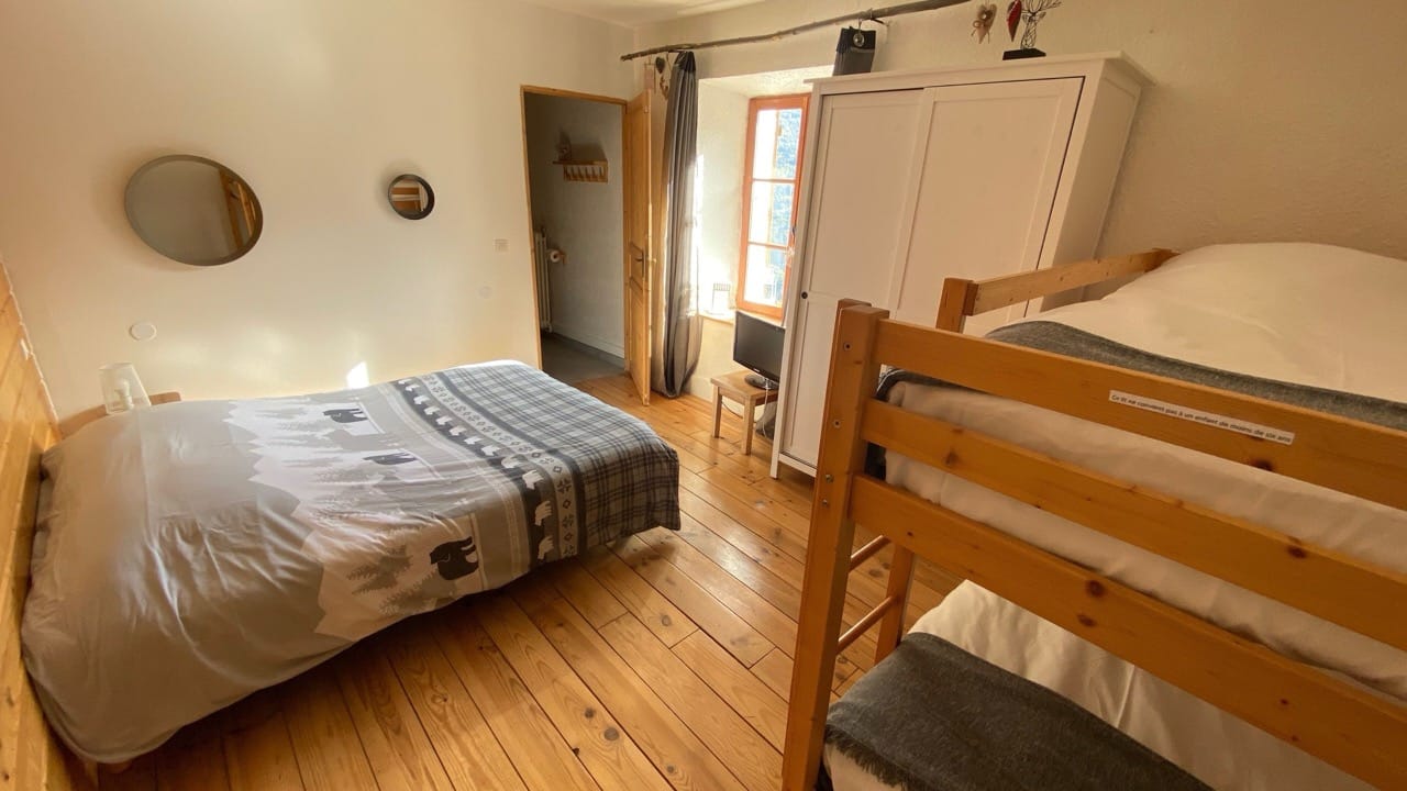 Bedroom at Auberge De La Foret Auris with one bed one double deck bed wooden floors and white walls