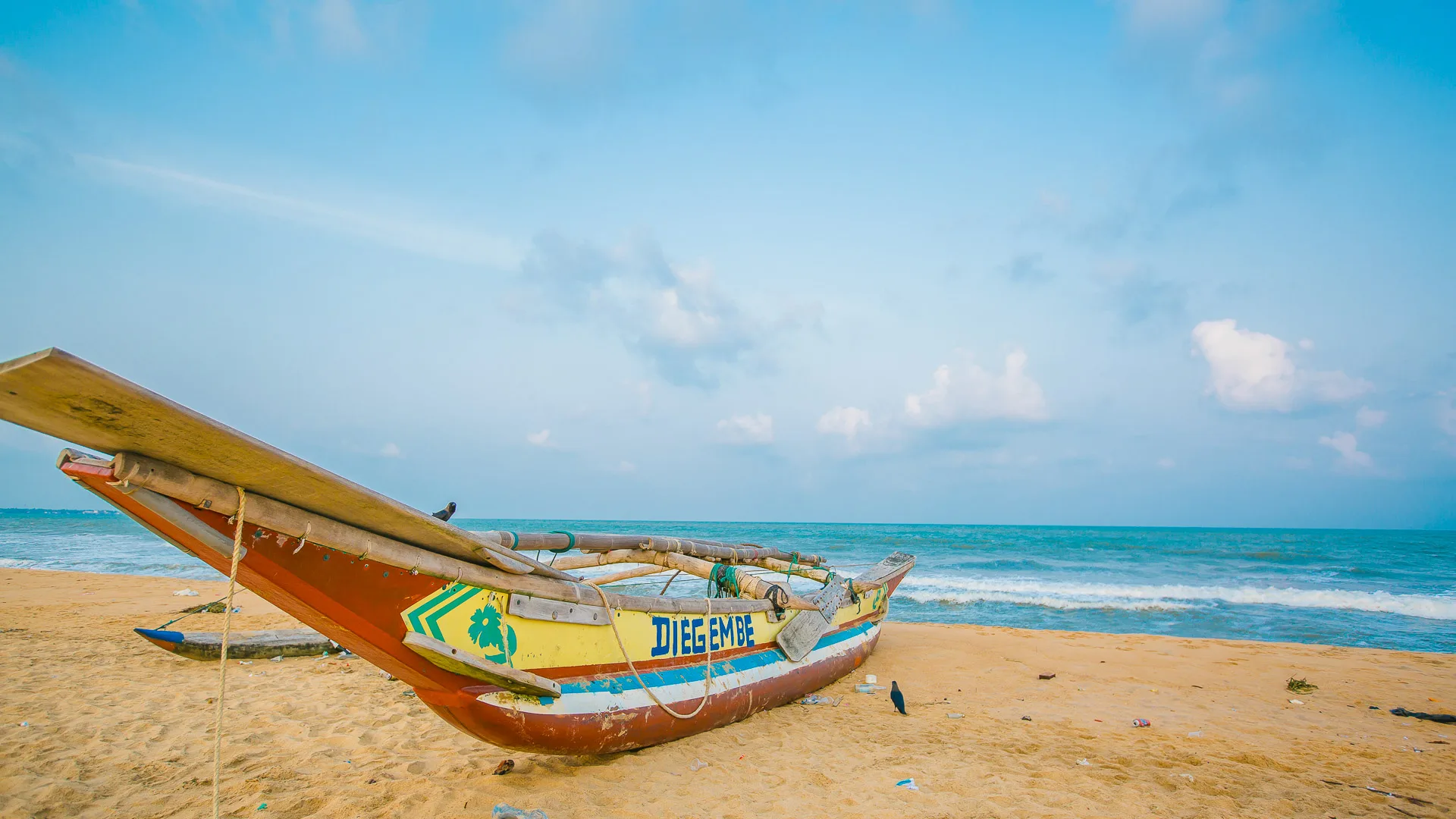 Traditional painted fishing boat resting on a beach in Sri Lanka with calm sea beyond