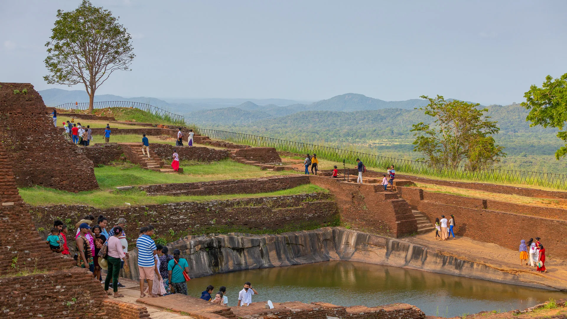 Visitors exploring terraced ruins and pond atop Sigiriya rock fortress in Sri Lanka’s cultural triangl
