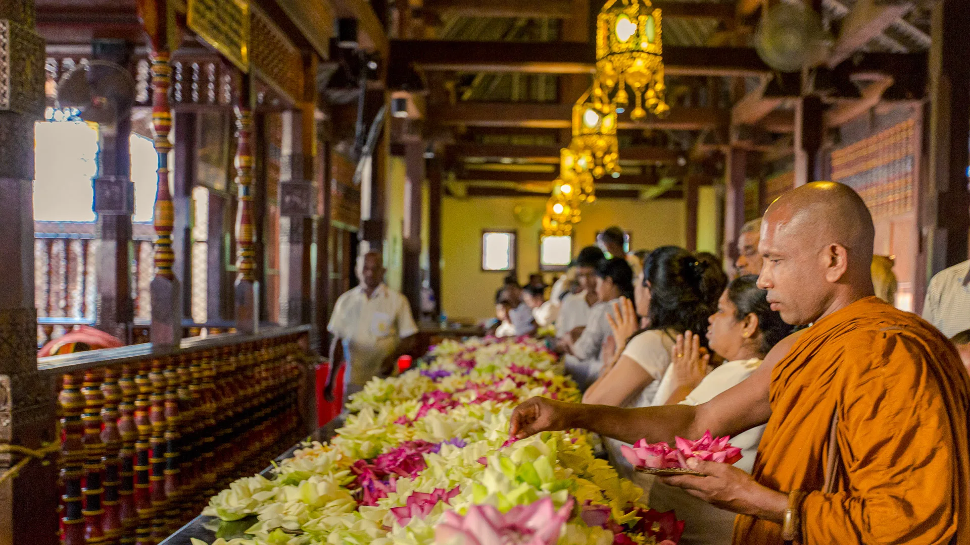 Monks and worshippers offering flowers inside a Buddhist temple in Sri Lanka