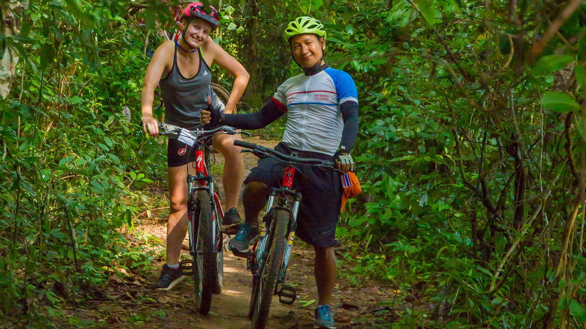 Cyclists on a forest trail surrounded by lush greenery