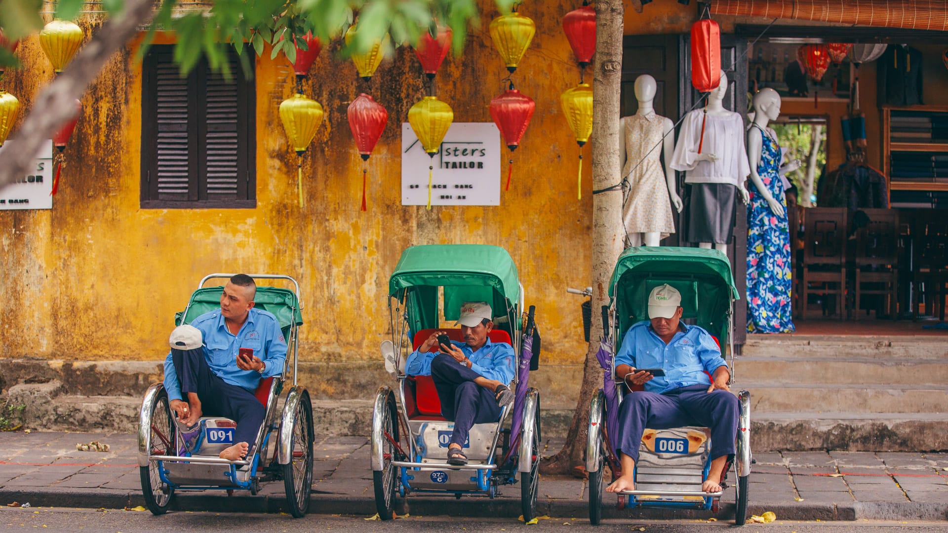 Cyclo drivers resting by yellow walls in Hoi An Vietnam