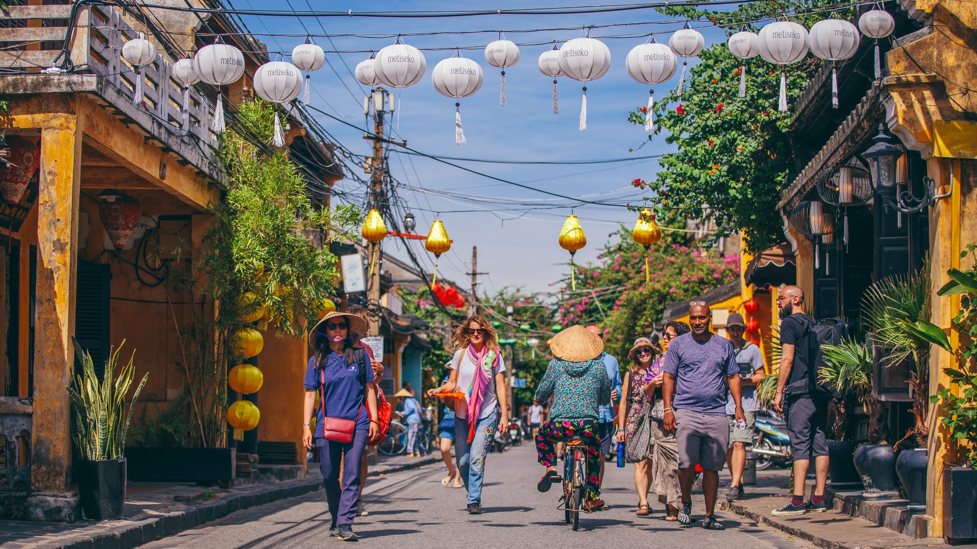 Tourists walking under lanterns in a busy street in Hoi An Vietnam
