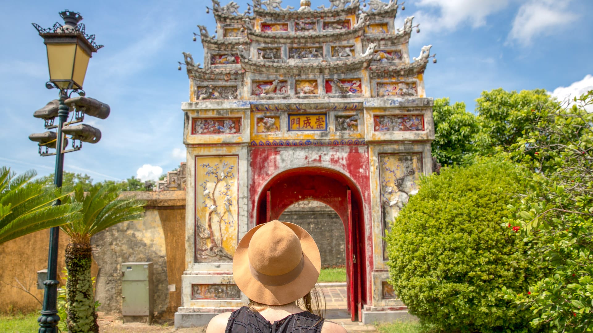 Woman admiring ornate red and yellow gateway at Hue Citadel