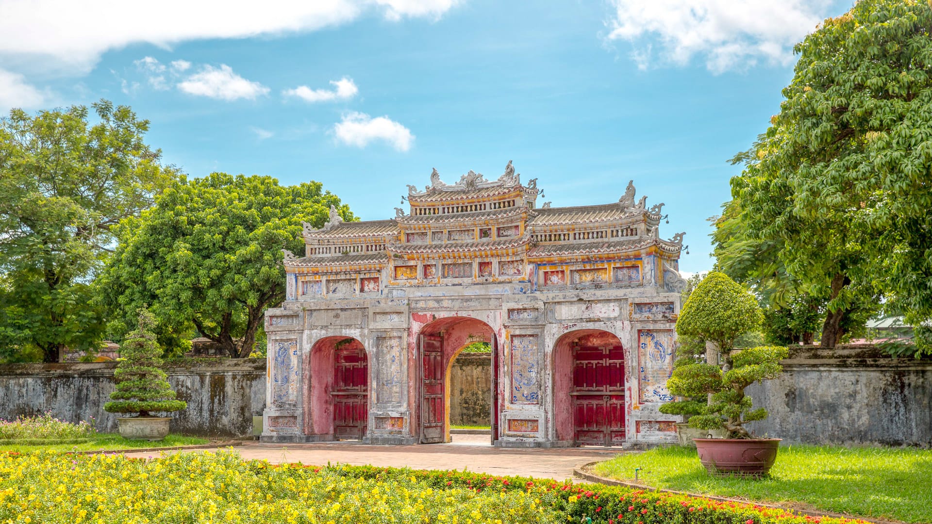 Ornate Hien Nhon Gate at Imperial Citadel in Huế, Vietnam surrounded by manicured gardens and lush green trees