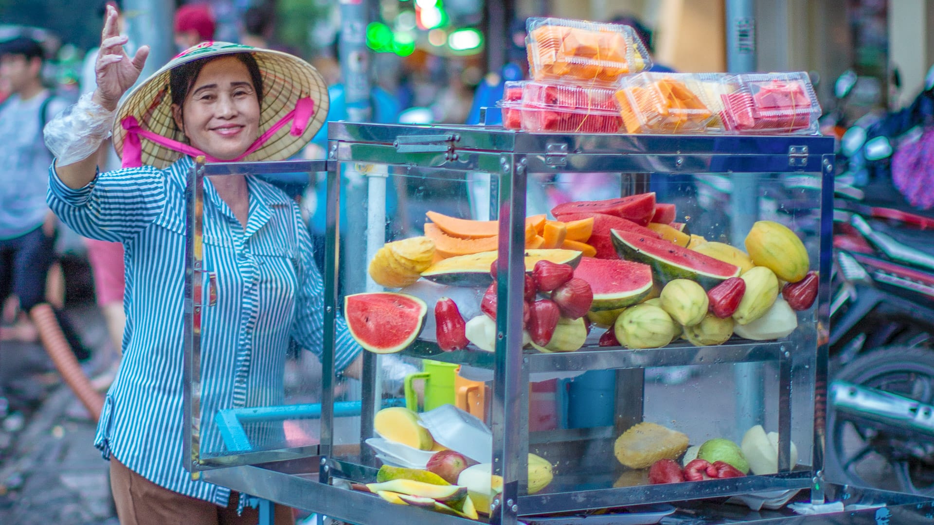 Smiling woman selling tropical fruits from a street cart in Ho Chi Minh City, Vietnam