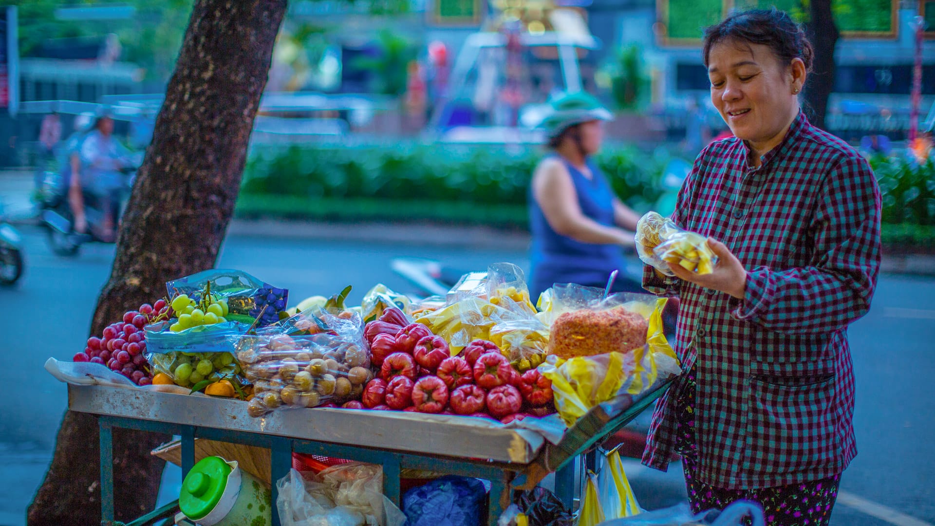 oman selling tropical fruits from a cart in Ho Chi Minh City
