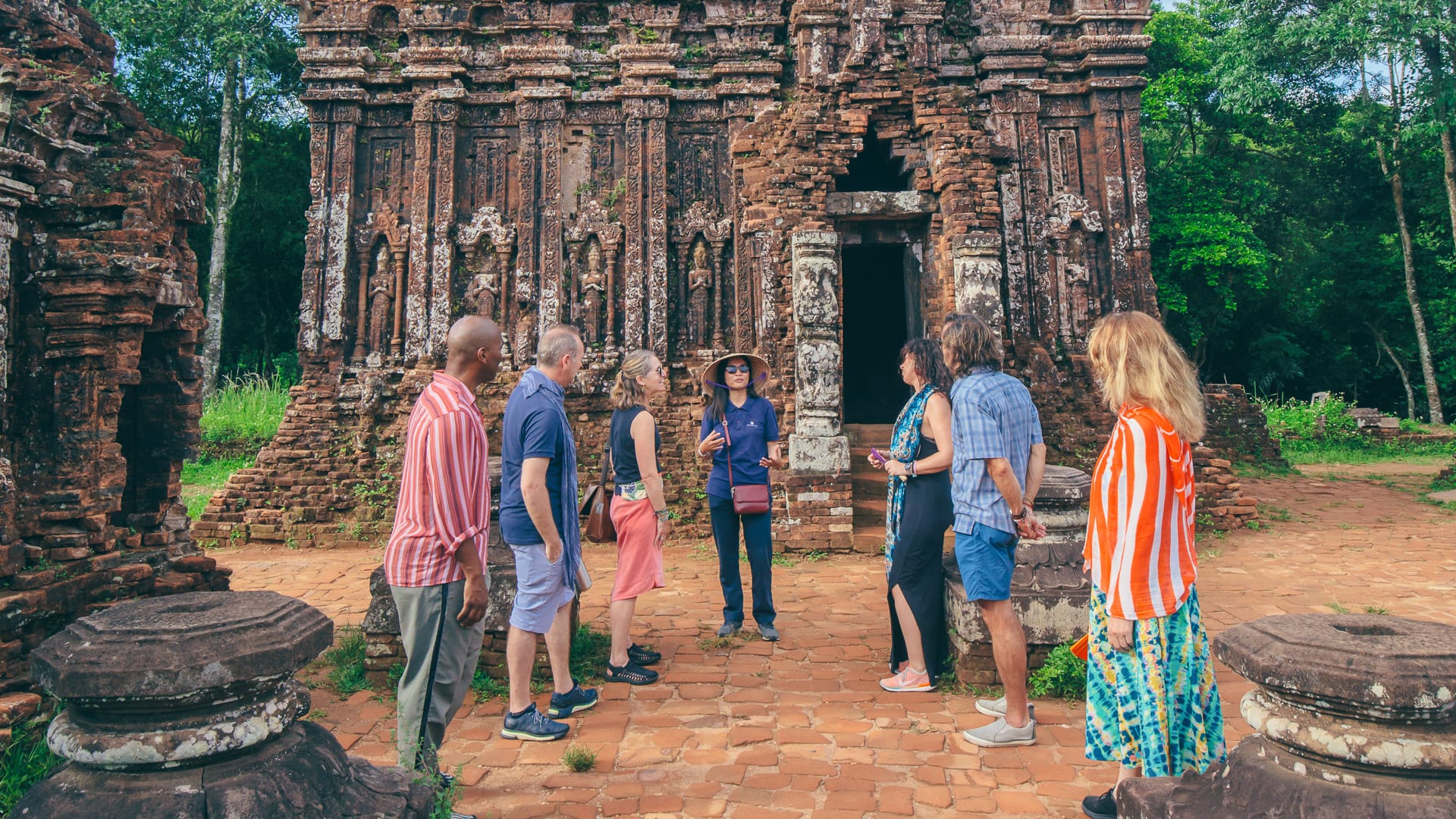 Tour guide leading group at ancient brick temple in Mỹ Sơn Sanctuary near Hoi An, central Vietnam