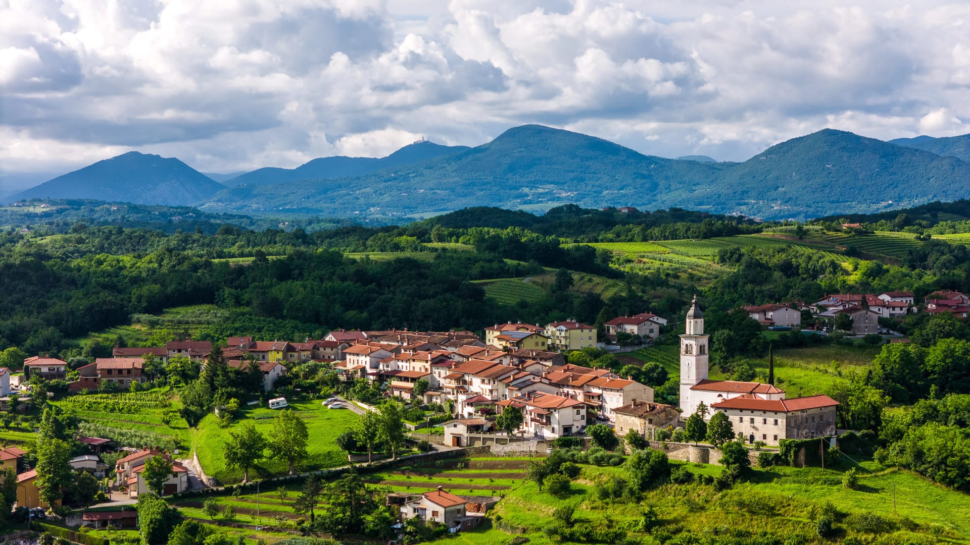 Hilltop village and church surrounded by rolling green hills in Vipava Valley, Slovenia