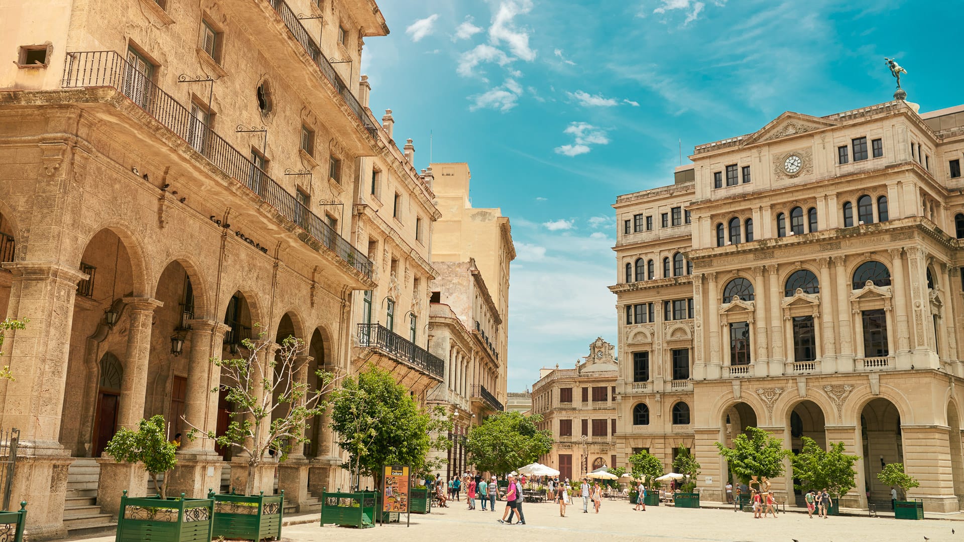 Elegant colonial-era buildings surrounding a sunlit square in Old Havana, Cuba