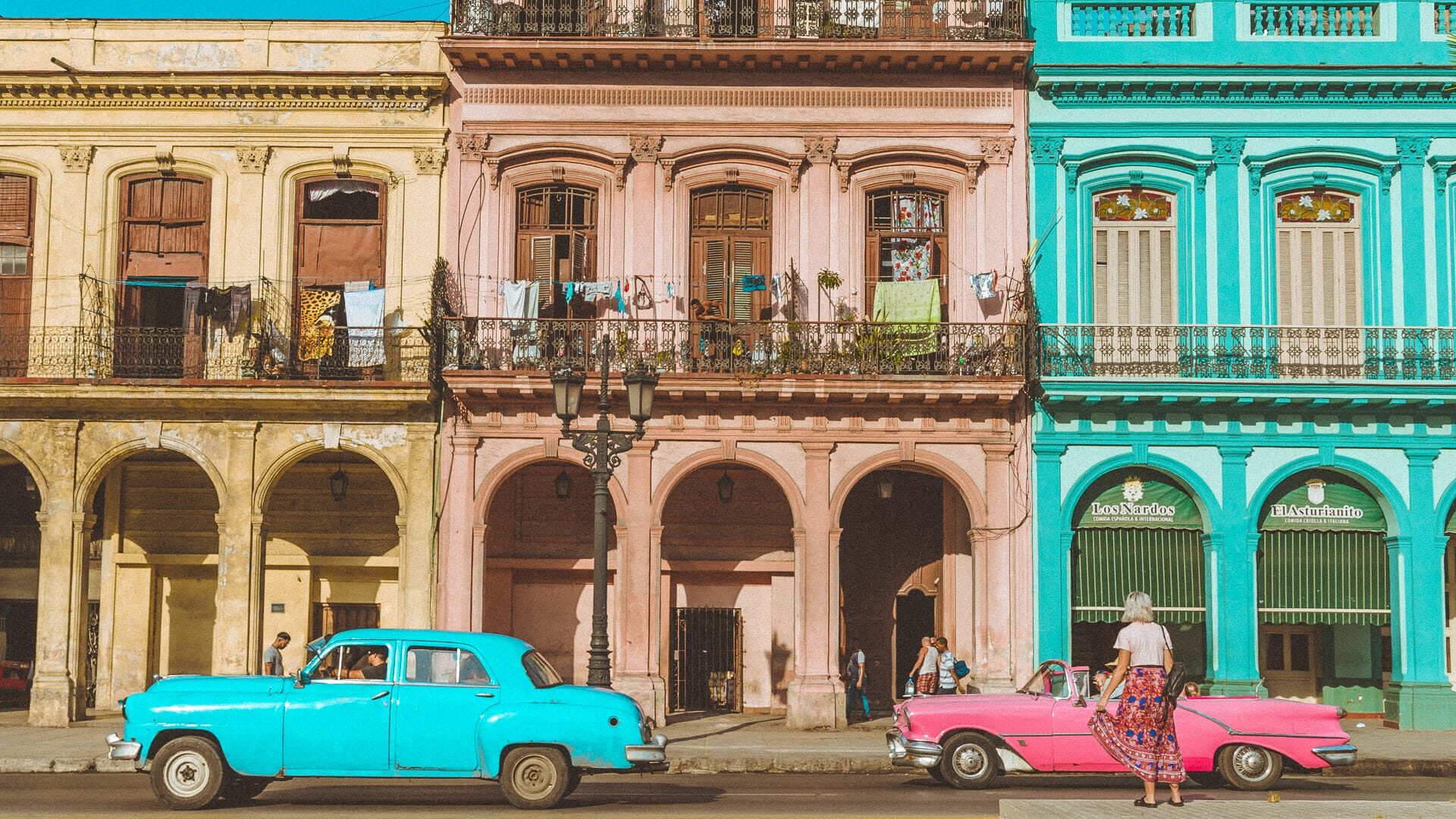 Bright vintage cars and pastel colonial buildings on a vibrant street in central Havana, Cuba
