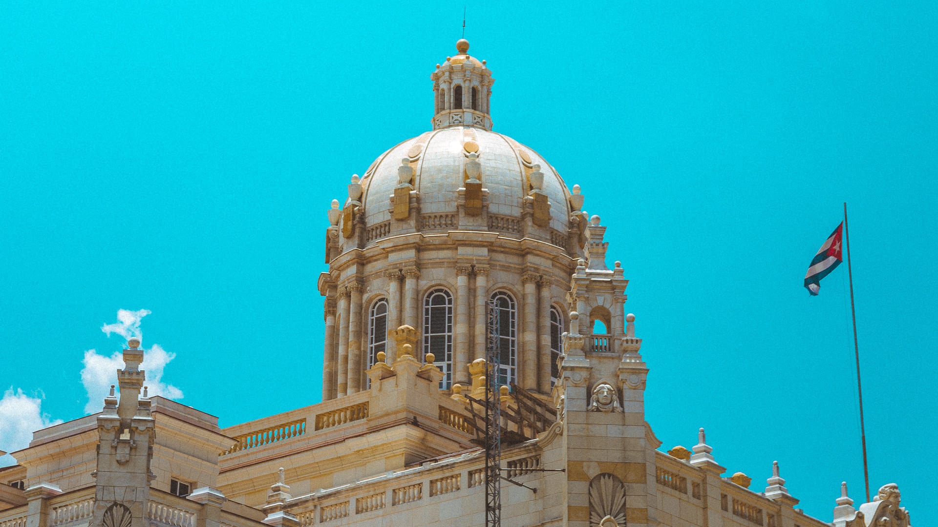The ornate dome of the Museum of the Revolution in Havana, Cuba, with the Cuban flag nearby