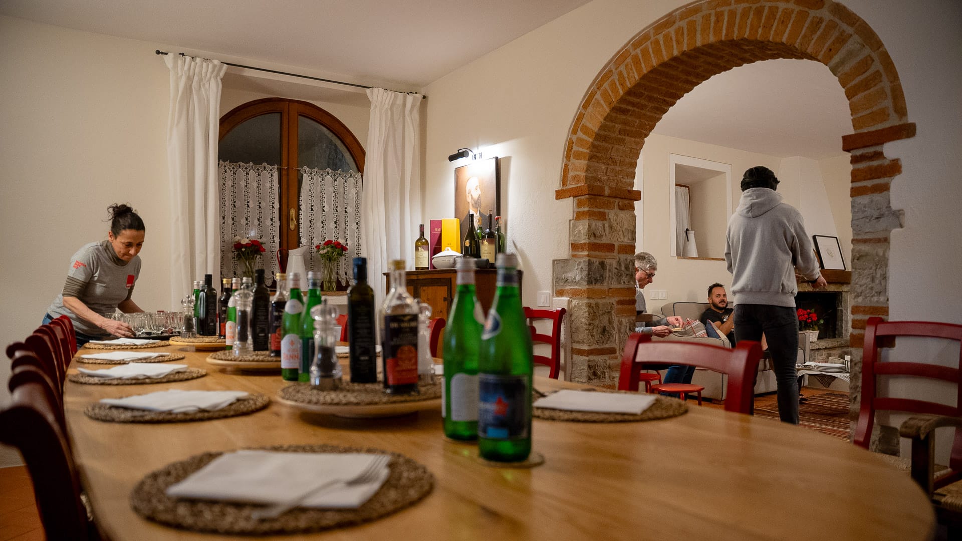 Long wooden table set for dinner in a warm rustic villa with arched doorway