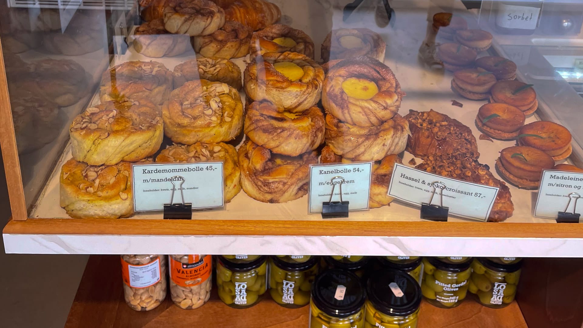 Display of cinnamon buns and pastries at a bakery in Grimstad with jars of local products below