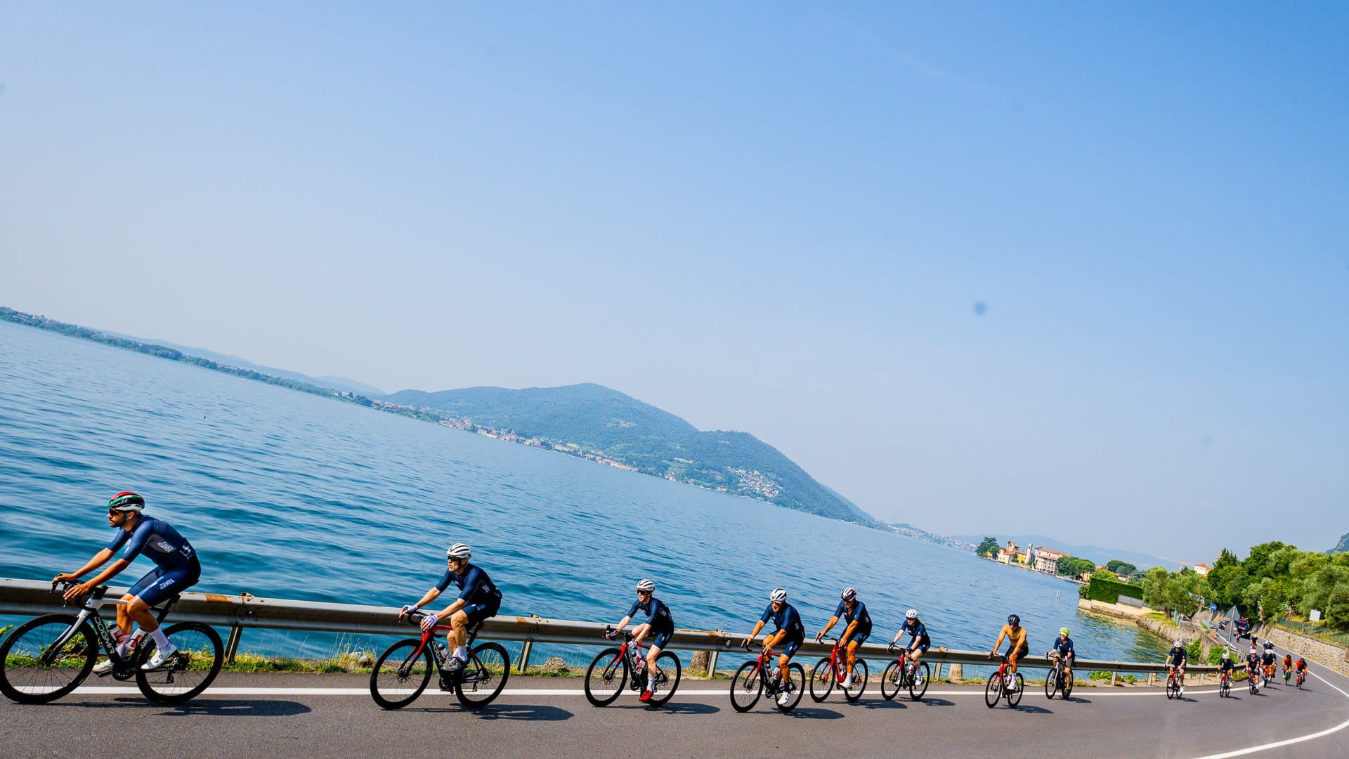 Cyclists riding beside a tranquil lake with mountain views