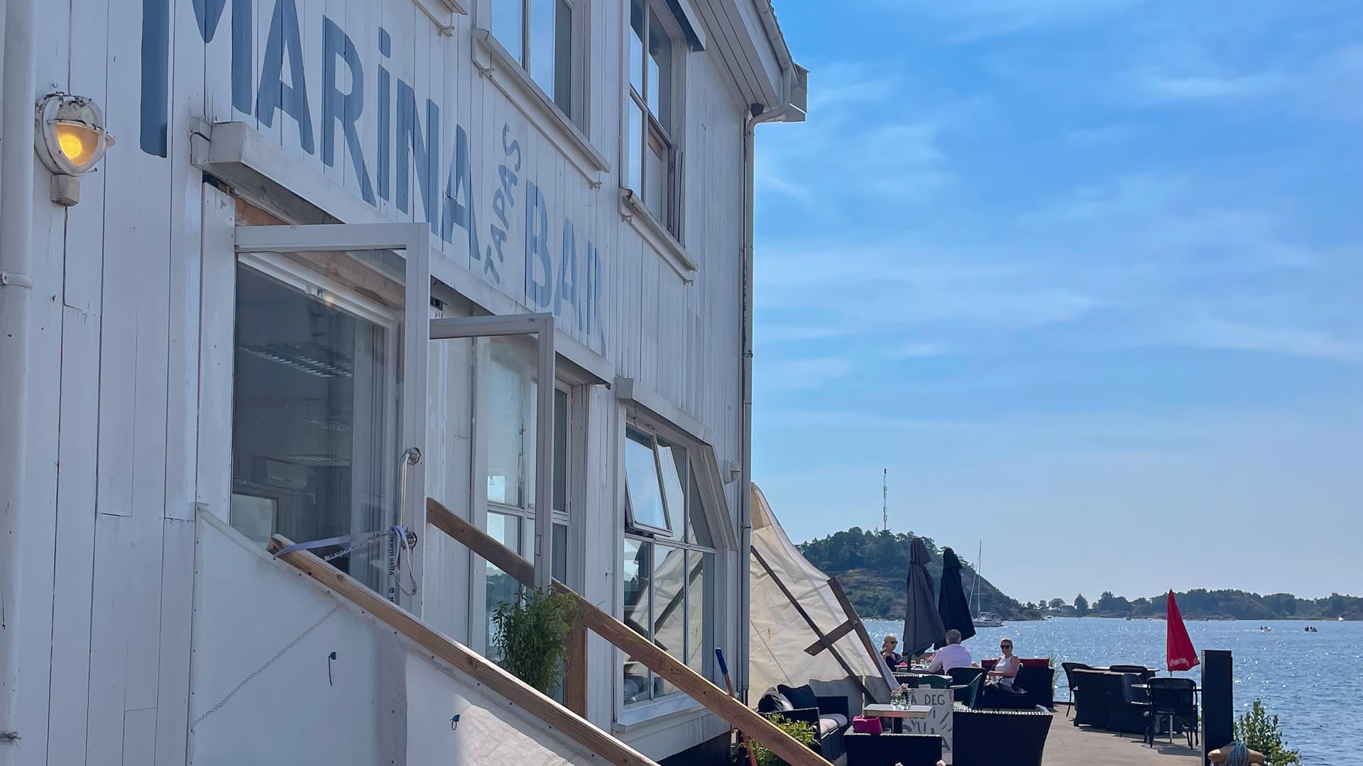 White marina café with outdoor seating overlooking the harbourfront in Grimstad