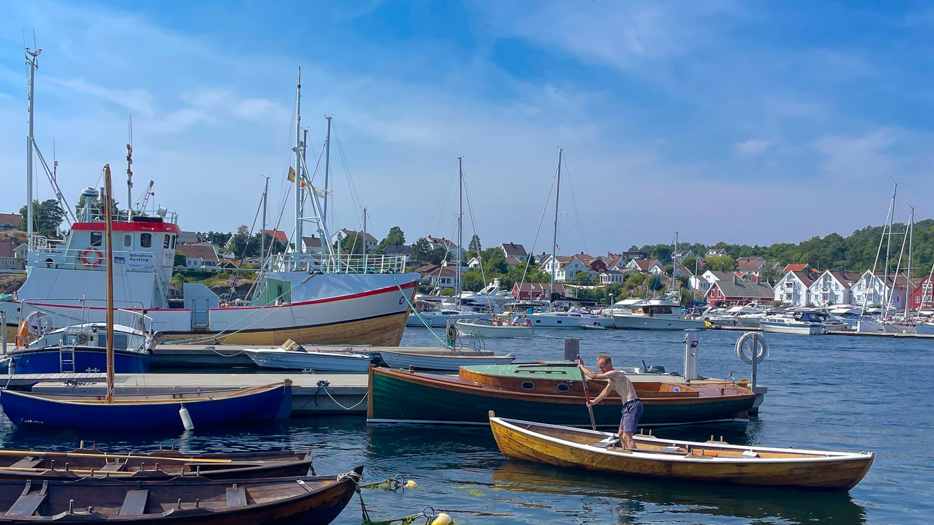 Wooden rowboats and fishing vessels moored in scenic Lillesand harbour in southern Norway