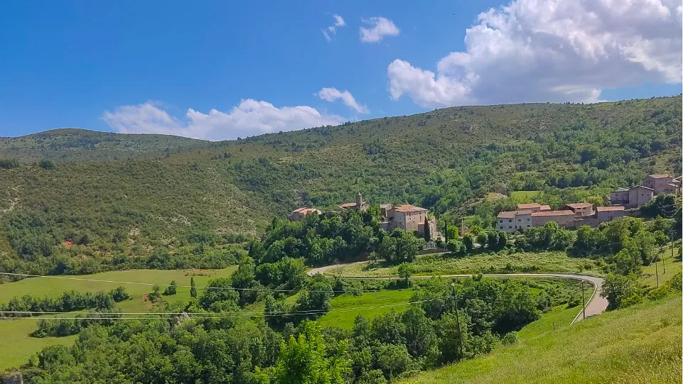 Village of Perves nestled in green hills, seen from Creu de Perves climb in the Spanish Pyrenees