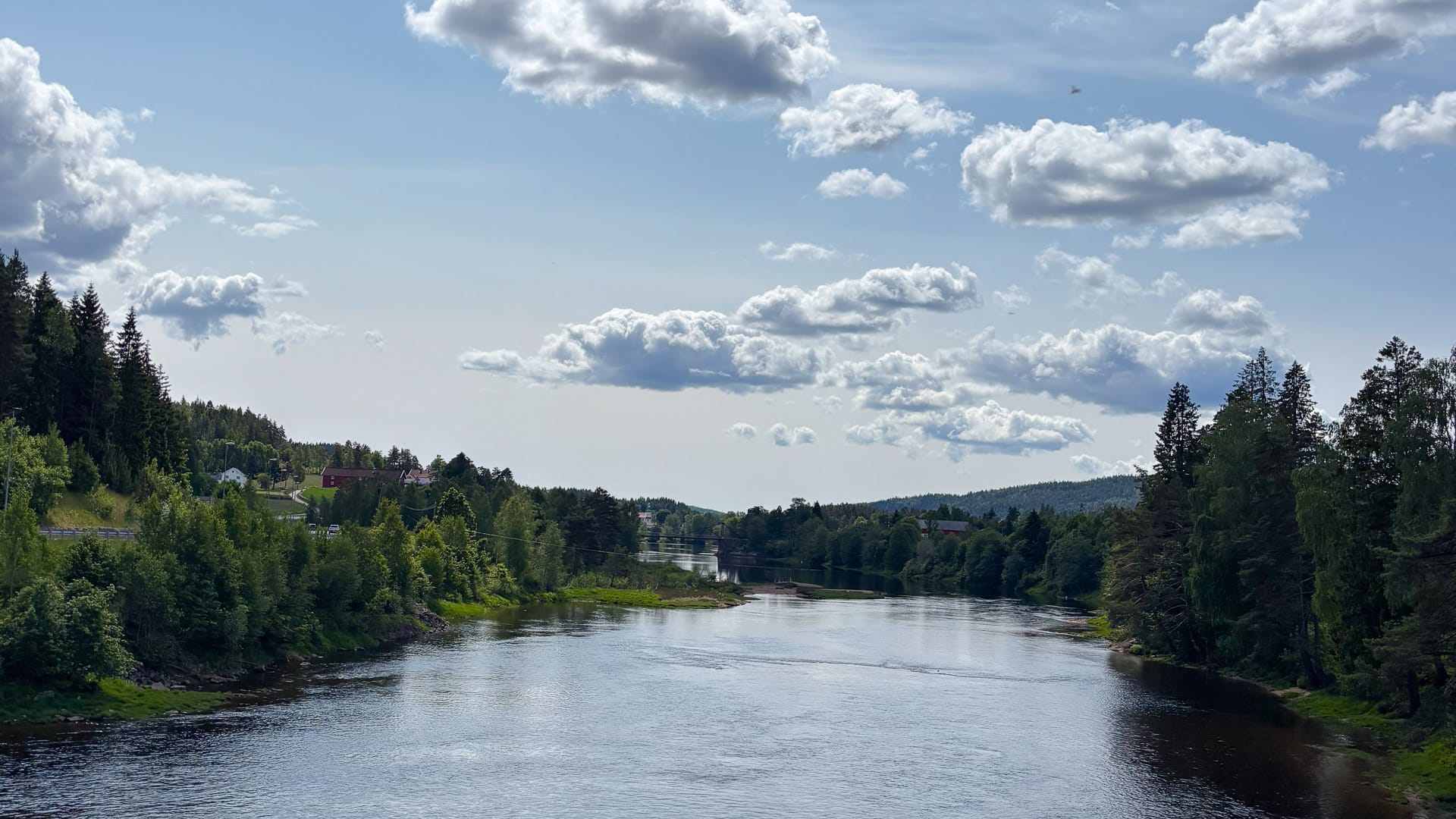 View of the Tovdal river near Rugsland with forested banks and scattered clouds above