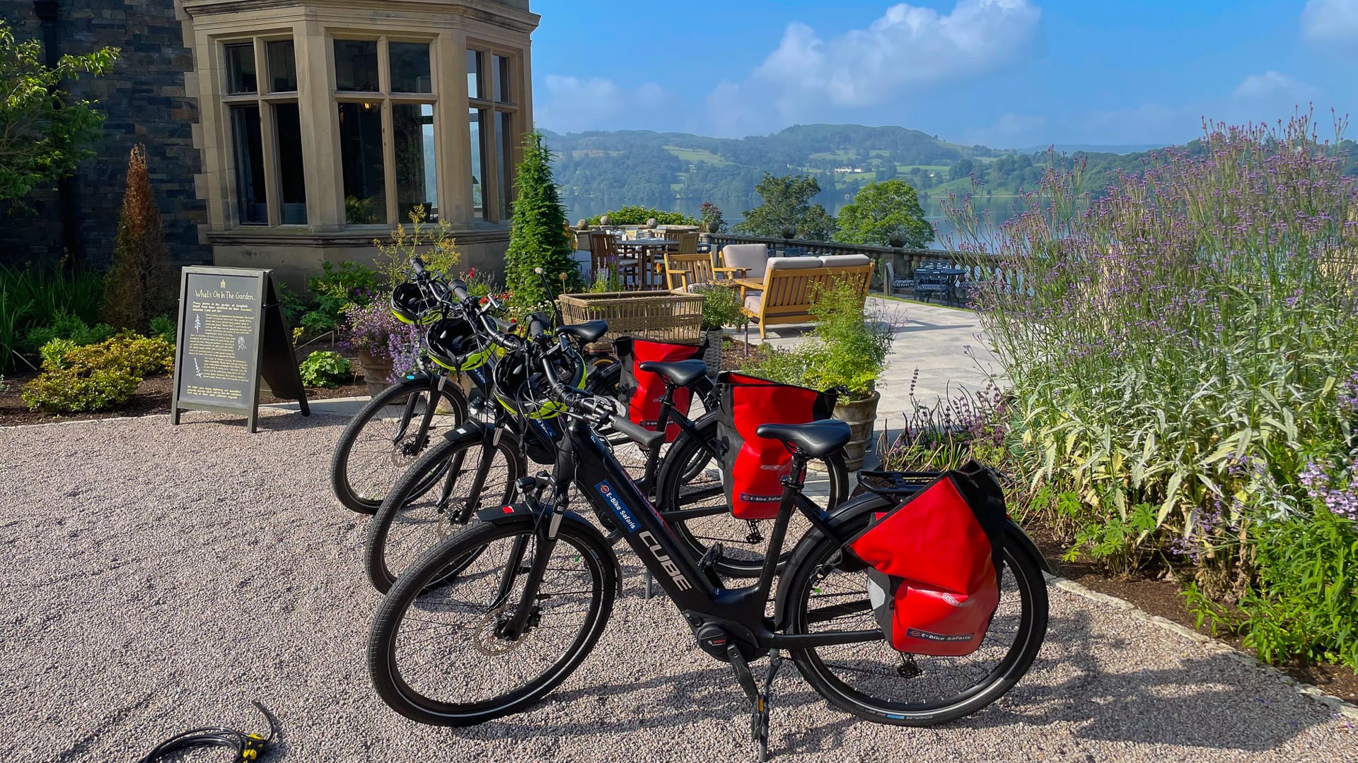 Row of e-bikes with red panniers outside garden café in Windermere Lake District