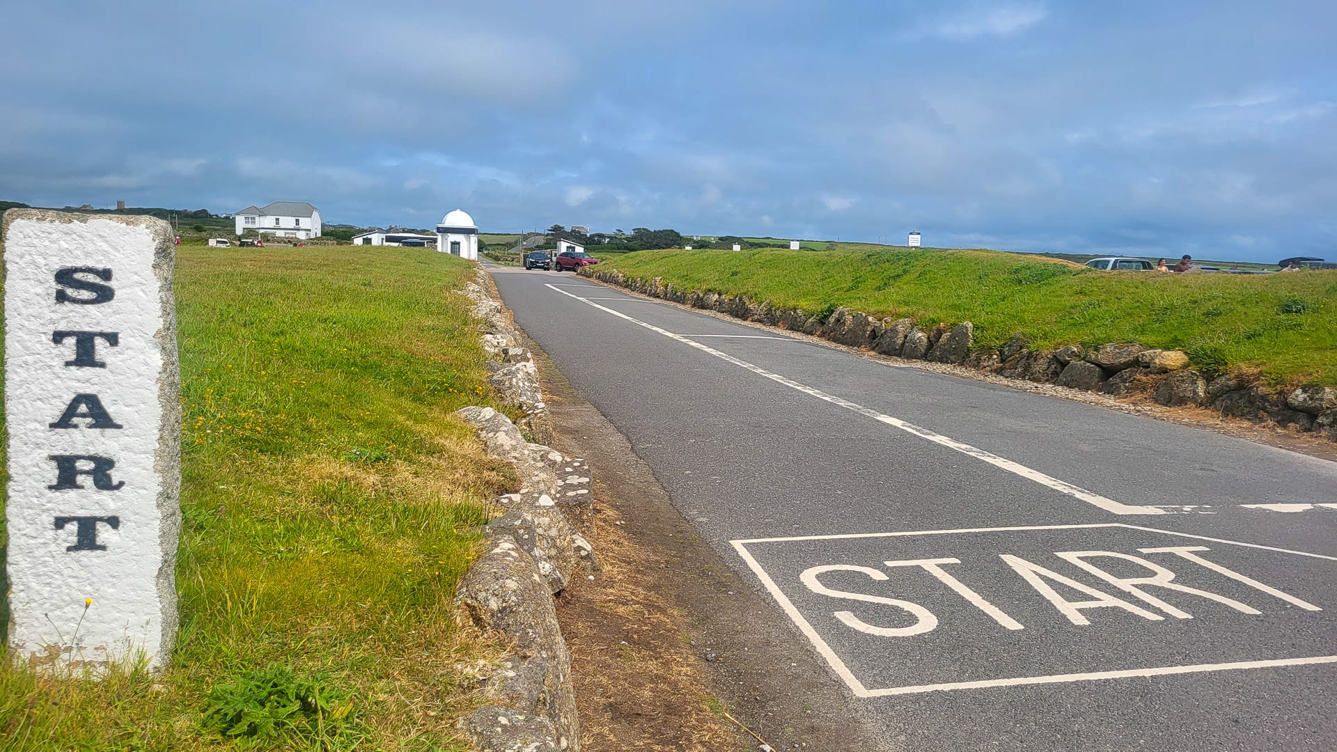 ‘Start’ line painted on road with stone marker at the beginning of cycling route