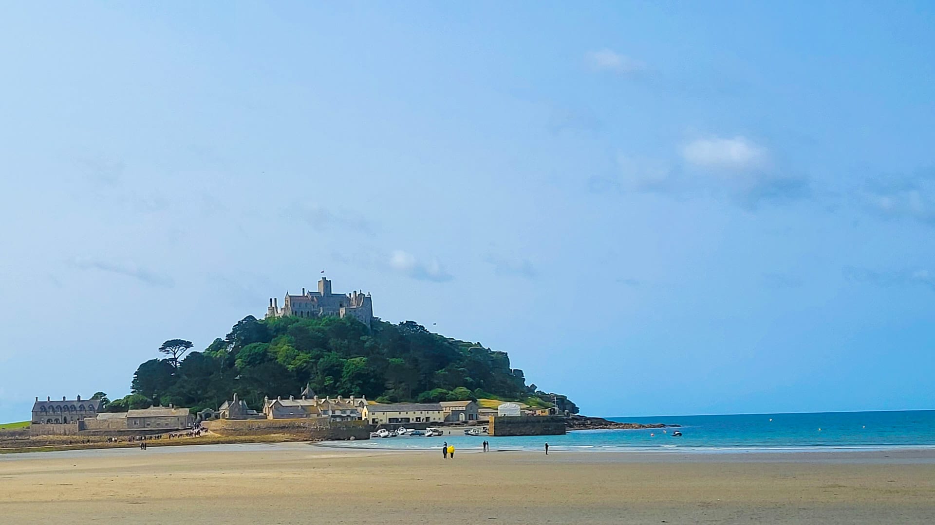 View of St Michael’s Mount and sandy beach with people walking at low tide
