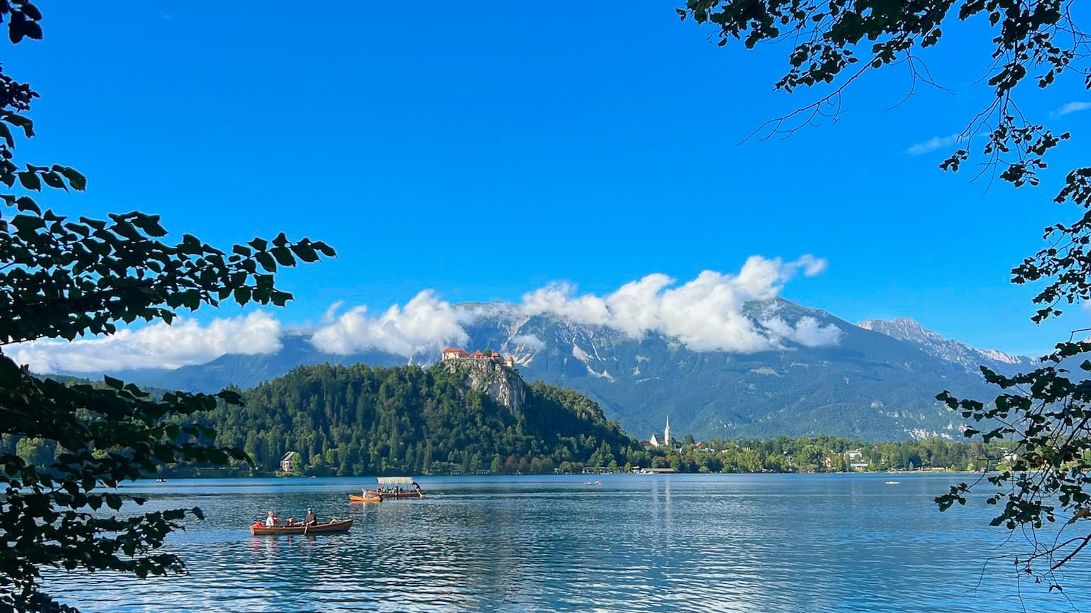 Lake Bled with castle on the hill, church spire and boats on the water