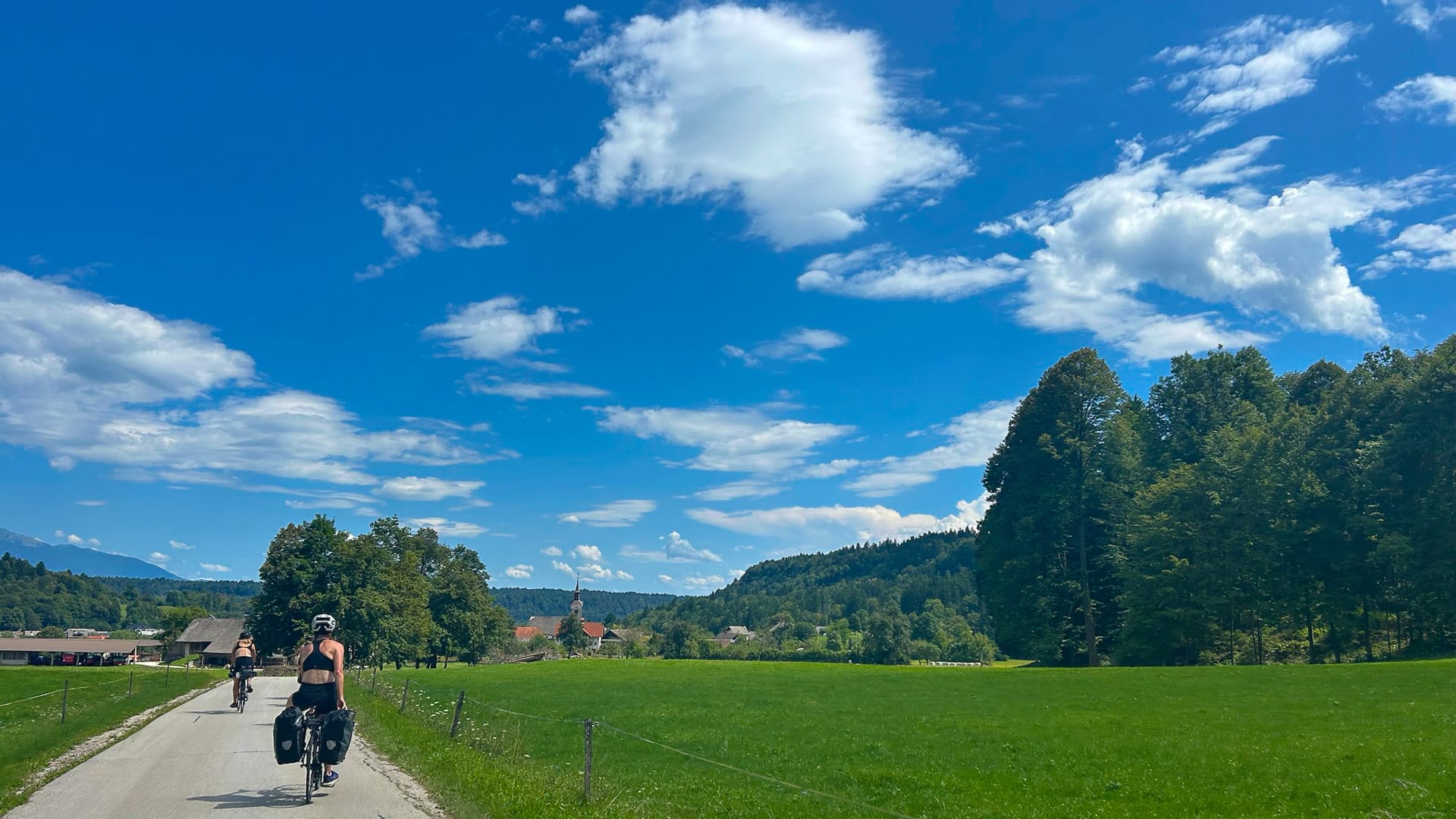 Cyclists riding countryside road between Bled and Ljubljana on a sunny day
