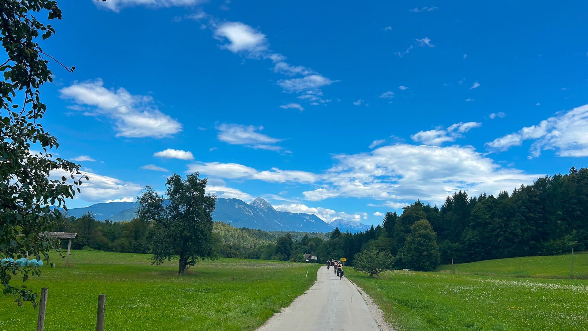 Cyclists on country road between Bled and Ljubljana with mountains ahead