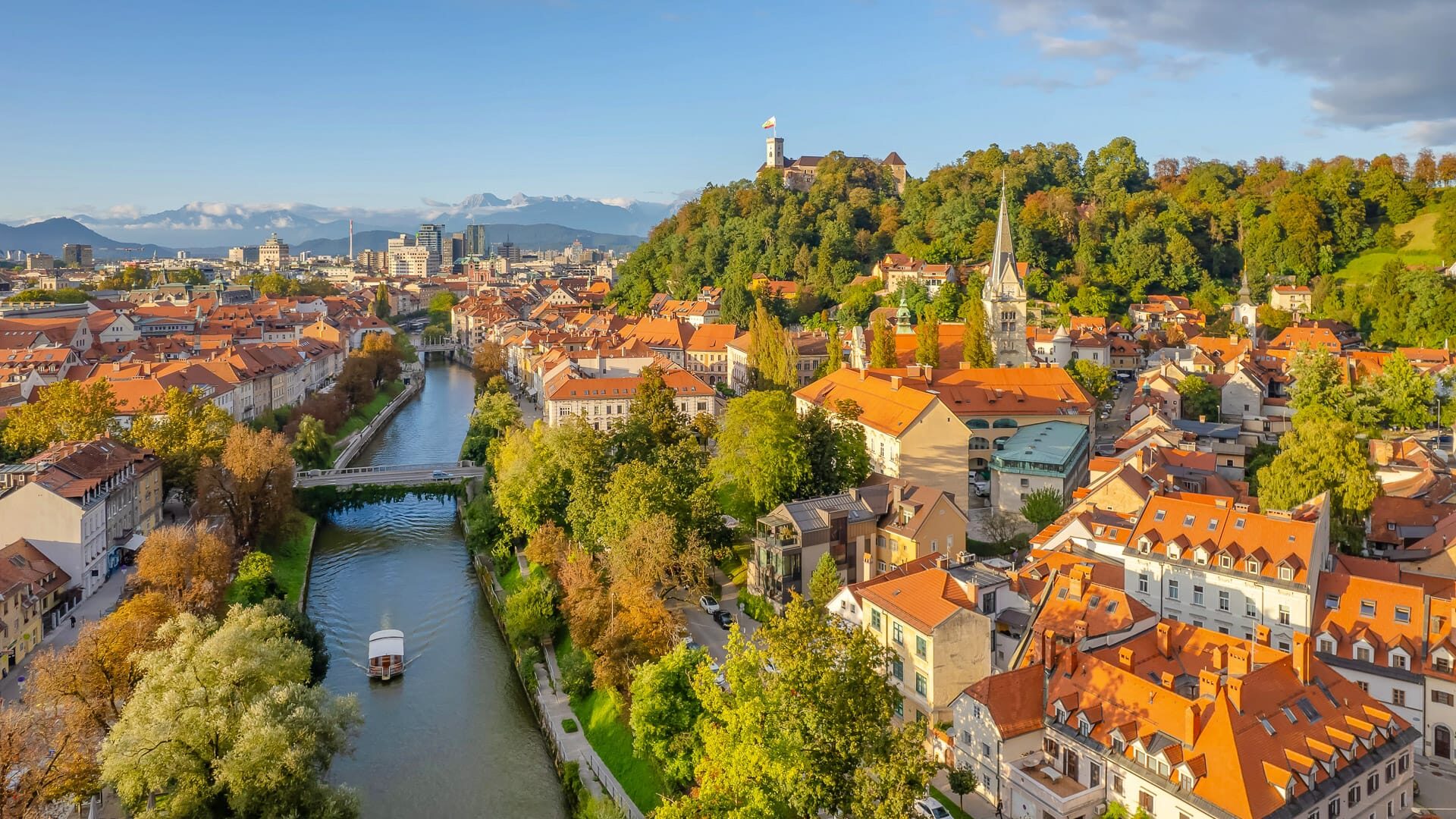 Aerial view of the Ljubljana old town at autumn, Slovenia. Ljubljana castle, historic buildings and Ljubljanica river in Slovenian capital at sunny day. Beautiful mountain range at background