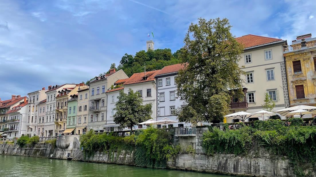 Ljubljana riverside cafés with castle tower visible on the hill above