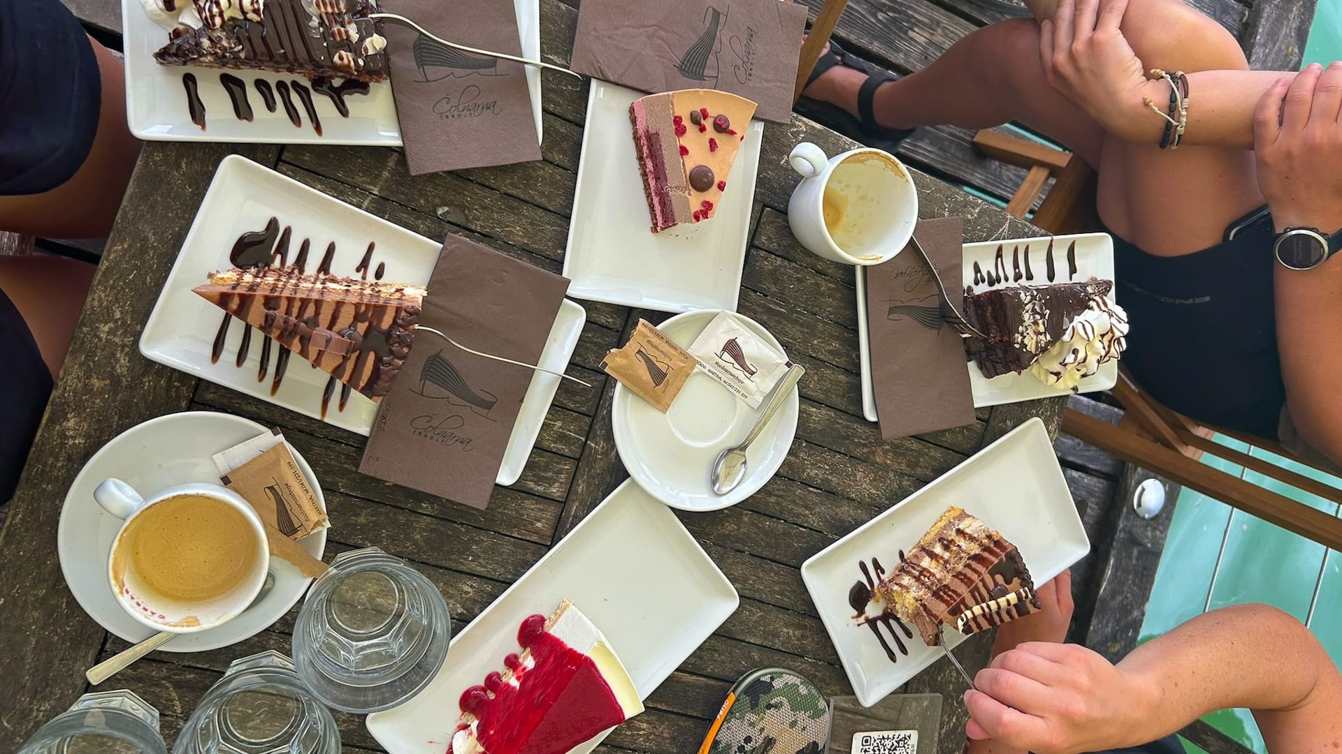Plates of cakes and coffee on a wooden café table at Colnarna Trboje
