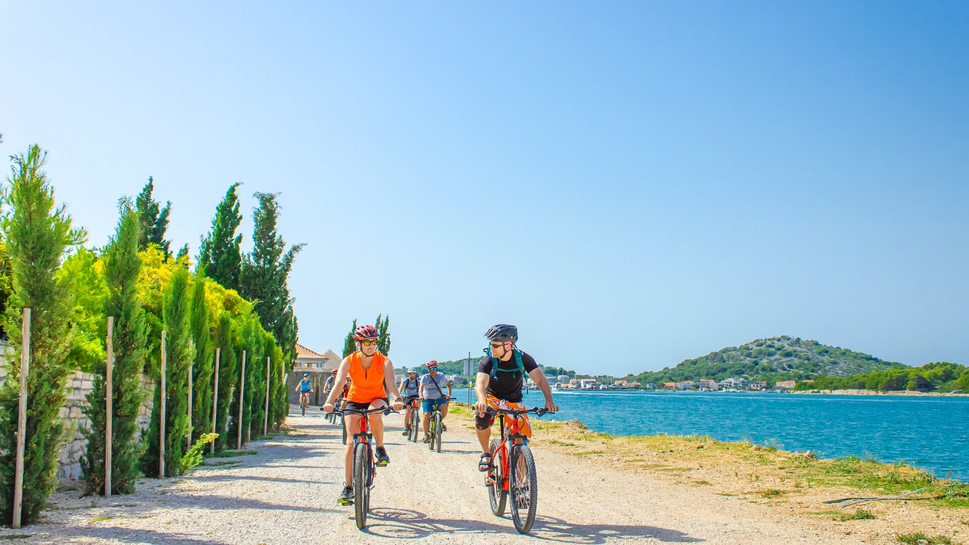 Cyclist enjoying a scenic coastal view in Murter, Croatia, with turquoise waters and pine trees