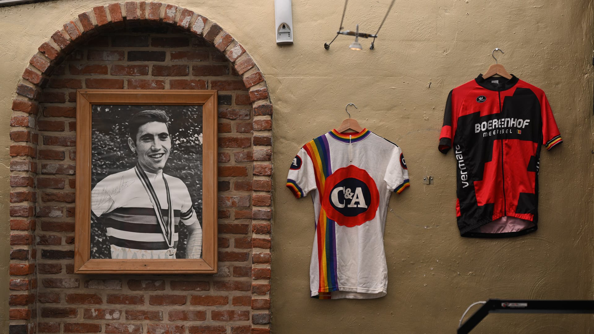 Display of Eddy Merckx memorabilia with cycling jerseys and portrait at café stop in Flanders