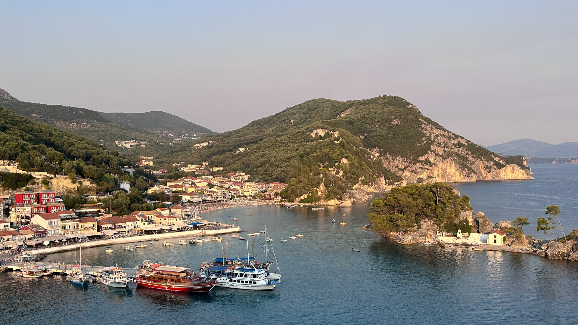 Boats docked in the harbour of Parga with hills rising behind the town