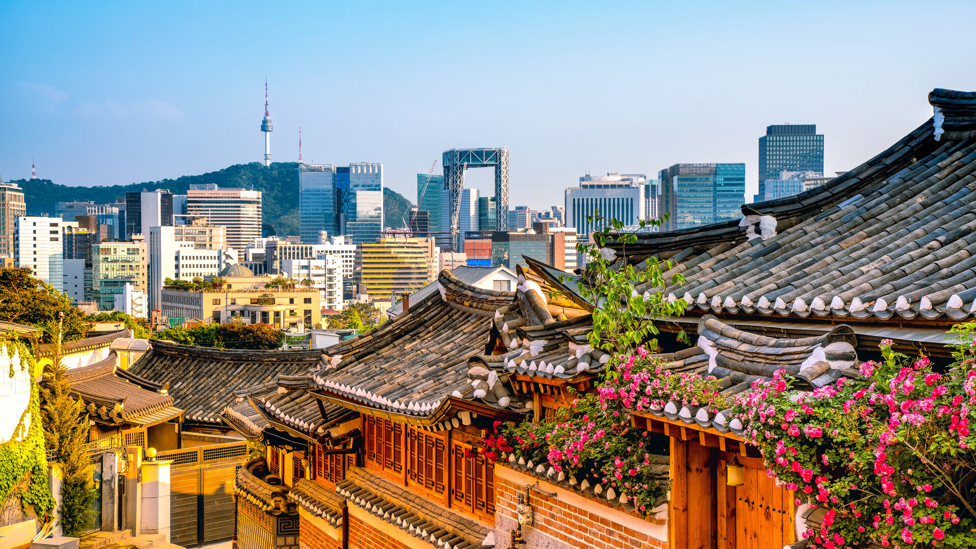 Traditional hanok village in Seoul with city skyline and Namsan Tower in the background