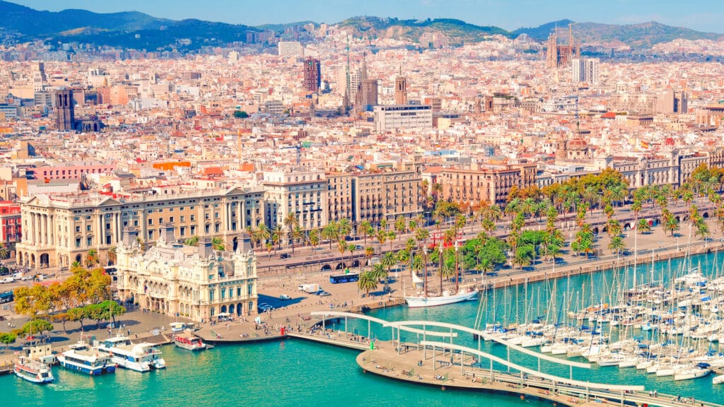 Aerial view of Barcelona’s Port Vell with yachts, palm-lined waterfront and the city skyline