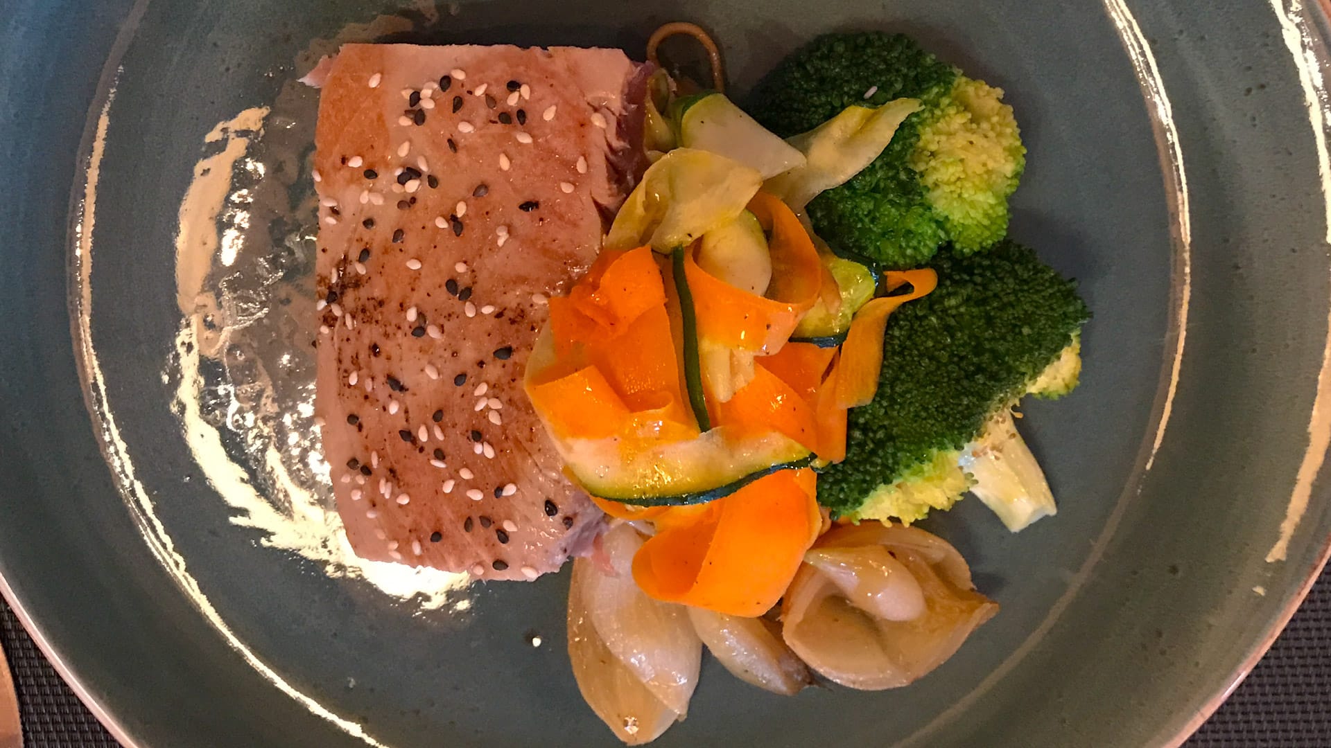 Gourmet plated dish featuring sesame-crusted tuna steak topped with ribboned carrots and zucchini