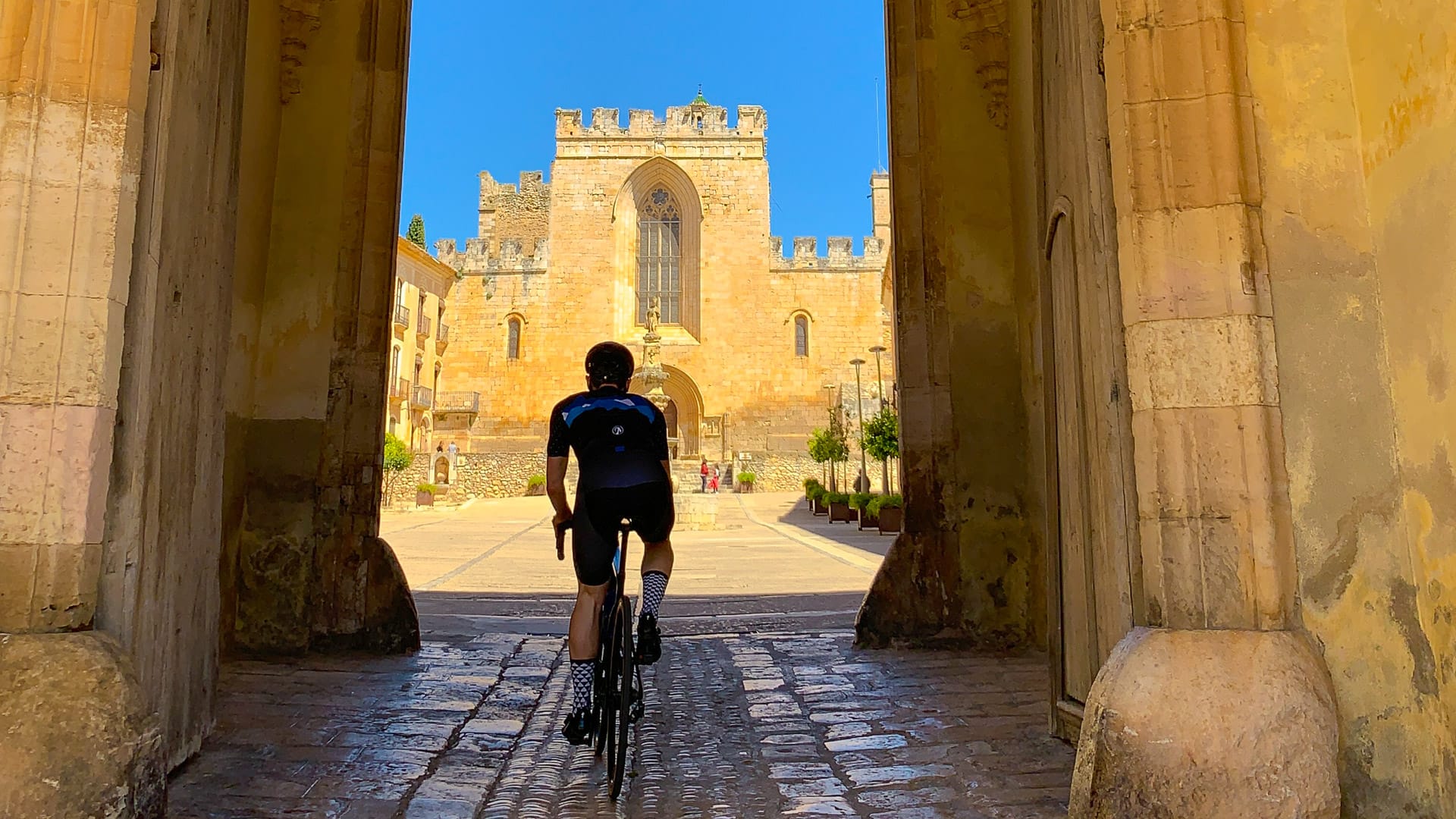 Cyclist entering Santa Creus monastery building complex