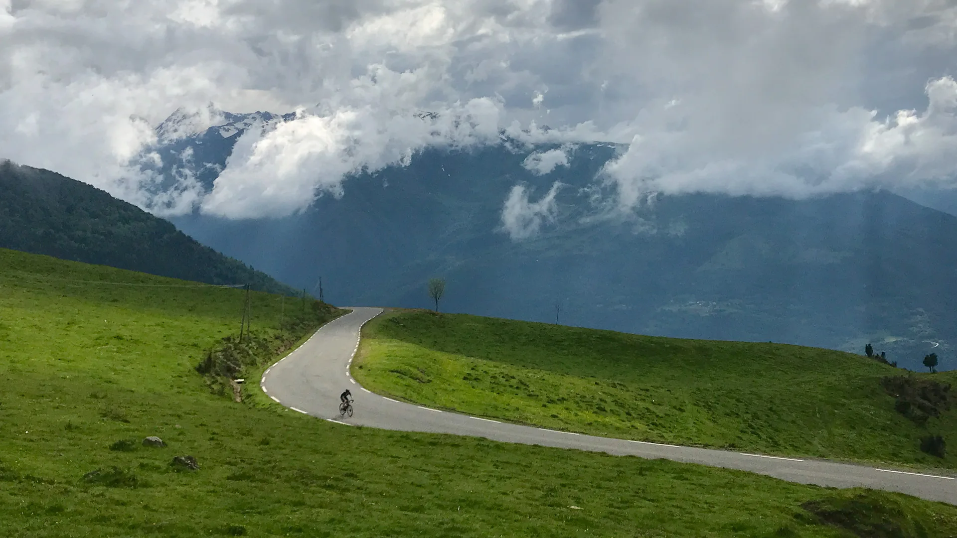 Cyclist on open road near top of Hautacam with thick cloud above