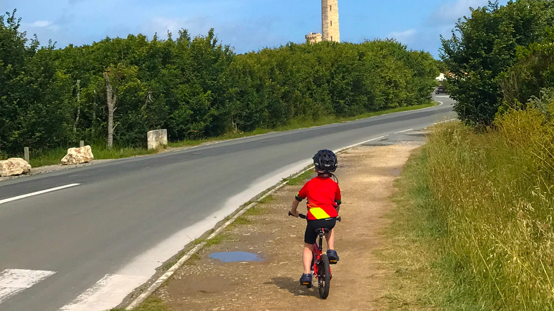 Child cycling towards Phare des Baleines lighthouse
